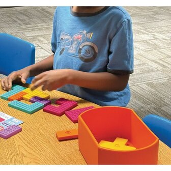 Persoon legt kleurrijke siliconen vormen van de Geri-Gadgets Shapes Bucket op tafel, een activiteit die concentratie en tastzin