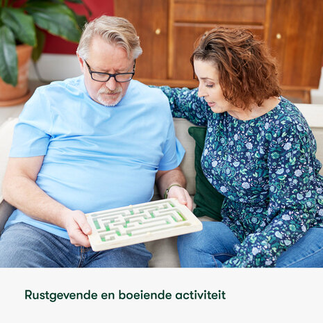 Man met dementie en mantelzorger spelen samen met het knikkerdoolhof &ndash; rustgevende activiteit voor stimulatie en contact